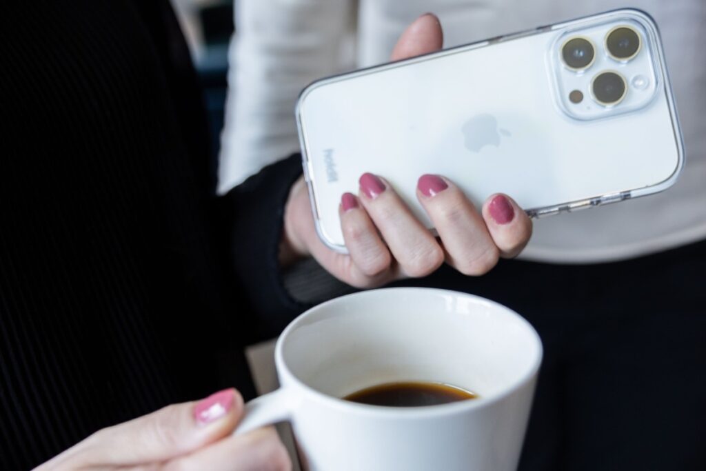 tjej med mobil och kaffekopp