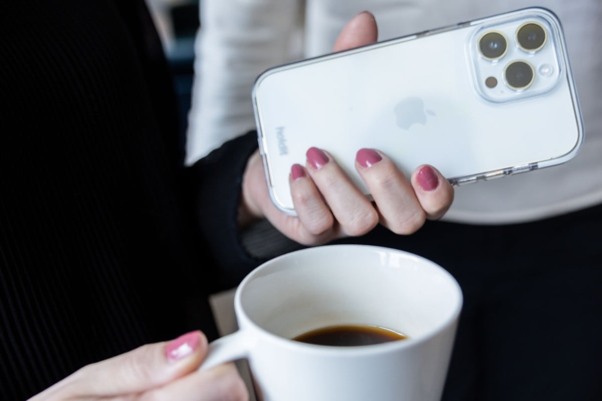 tjej med mobil och kaffekopp